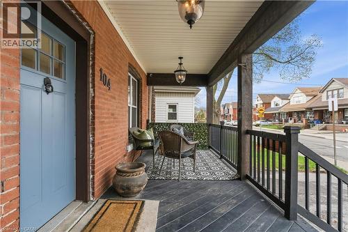 Inviting covered porch featuring a brick exterior and a light blue entry door with transom window - 104 Barnesdale Avenue N, Hamilton, ON - Outdoor With Deck Patio Veranda With Exterior