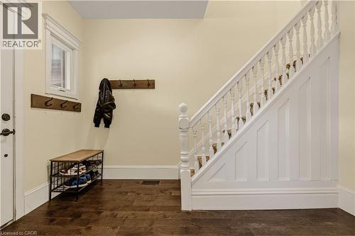 Entryway featuring dark wood-finish flooring, white baseboards, and a white staircase with turned balusters and paneled wainscoting - 104 Barnesdale Avenue N, Hamilton, ON - Indoor Photo Showing Other Room