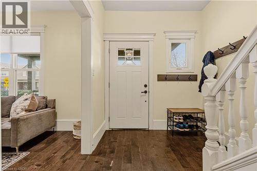 Entryway featuring a white paneled door with glass inserts, wood-finish flooring, white baluster staircase, and decorative wall trim - 104 Barnesdale Avenue N, Hamilton, ON - Indoor Photo Showing Other Room