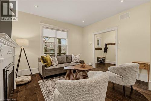 Living area featuring dark wood-finish flooring, recessed lighting, and a prominent white fireplace with detailed molding - 104 Barnesdale Avenue N, Hamilton, ON - Indoor Photo Showing Living Room