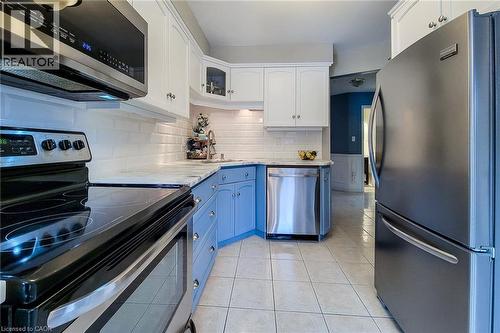 Kitchen featuring stainless steel appliances, white subway tile backsplash, light-toned countertops, two-tone cabinetry, and square tile flooring - 146 Locheed Drive, Hamilton, ON - Indoor Photo Showing Kitchen With Stainless Steel Kitchen