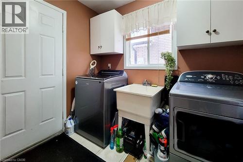 Dedicated laundry space featuring a utility sink with a chrome faucet, overhead cabinetry, and a window providing natural light - 146 Locheed Drive, Hamilton, ON - Indoor Photo Showing Laundry Room