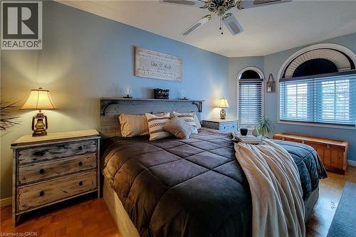 Light blue walls frame the room, featuring wood-finish flooring and a ceiling fan with integrated lighting - 146 Locheed Drive, Hamilton, ON - Indoor Photo Showing Bedroom