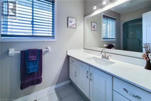 Bathroom featuring a white vanity with an integrated sink, brushed nickel faucet, and a large framed mirror - 146 Locheed Drive, Hamilton, ON - Indoor Photo Showing Bathroom