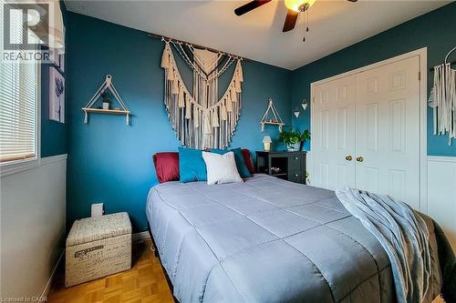Bedroom featuring teal walls, wood-finish flooring, white bi-fold closet doors, a ceiling fan with integrated lighting, and a window with horizontal blinds - 146 Locheed Drive, Hamilton, ON - Indoor Photo Showing Bedroom