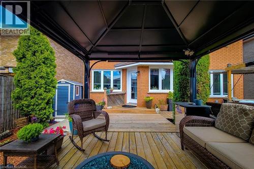Covered outdoor patio area featuring a light wood-finish deck, black metal gazebo structure, and a built-in fire pit - 146 Locheed Drive, Hamilton, ON - Outdoor With Deck Patio Veranda With Exterior