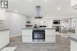 Kitchen island featuring a built-in stainless steel oven, cooktop, and overhead range hood - 