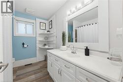 Bathroom featuring a single vanity with storage cabinetry, integrated sink, and an overhead light fixture - 