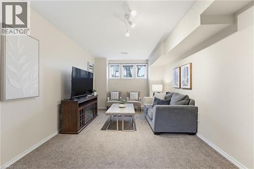 Carpeted living area featuring track lighting, light-toned walls, and a built-in media console with an integrated fireplace - 29 Strong Court, Brantford, ON - Indoor