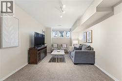 Carpeted living area featuring track lighting, light-toned walls, and a built-in media console with an integrated fireplace - 