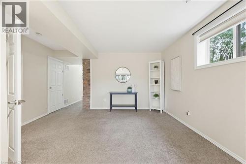 Carpeted room featuring a white interior door, a window with roller shade, and a brick accent wall - 29 Strong Court, Brantford, ON - Indoor Photo Showing Other Room