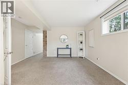 Carpeted room featuring a white interior door, a window with roller shade, and a brick accent wall - 