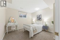 Bedroom featuring neutral wall paint, carpeted flooring, a window with blinds, and a ceiling-mounted light fixture - 