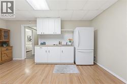 Compact kitchen area featuring white upper and lower cabinetry, a light-toned countertop, and a stainless steel sink - 