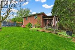 Expansive rear yard featuring a brick facade structure, a wooden deck, and a covered patio area - 