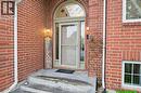 Brick exterior featuring an arched entry door with a storm door, concrete steps, and exterior lighting fixtures - 29 Strong Court, Brantford, ON  - Outdoor With Exterior 