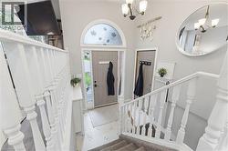 Entryway featuring a grey main door with an arched transom window, a white spindle staircase, and neutral wall tones - 