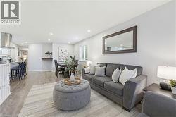 Open-concept living space with wood-finish flooring, recessed lighting, and ample natural light from a window with white blinds - 