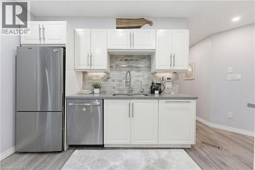 Kitchenette featuring white cabinetry, grey countertops, a stainless steel refrigerator, a stainless steel dishwasher, and a grey tile backsplash - 29 Strong Court, Brantford, ON - Indoor Photo Showing Kitchen