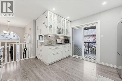 Contemporary kitchen cabinetry with glass-front upper cabinets, light gray countertops, and a full-height backsplash - 29 Strong Court, Brantford, ON - Indoor