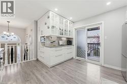 Contemporary kitchen cabinetry with glass-front upper cabinets, light gray countertops, and a full-height backsplash - 