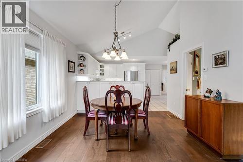 Vaulted ceiling dining area featuring wood-finish flooring, a contemporary chandelier, and a built-in wall niche - 422 Powerline Road Unit# 10, Brantford, ON - Indoor Photo Showing Dining Room