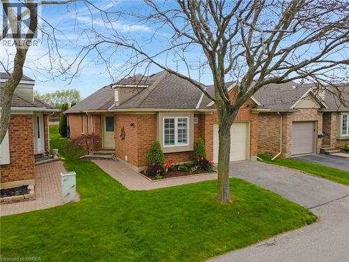 Brick exterior residence featuring a covered front entrance, bay window, and attached garage - 422 Powerline Road Unit# 10, Brantford, ON - Outdoor