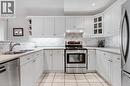 U-shaped kitchen featuring white cabinetry, light-toned countertops, subway tile backsplash, stainless steel appliances, and square floor tiles - 422 Powerline Road Unit# 10, Brantford, ON  - Indoor Photo Showing Kitchen With Stainless Steel Kitchen With Double Sink 