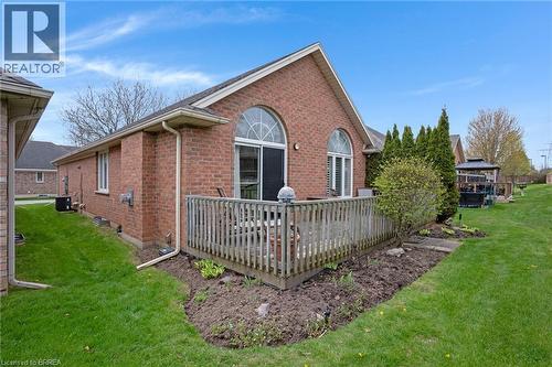 Brick exterior featuring a wooden deck with railing, arched windows, and a sliding glass door - 422 Powerline Road Unit# 10, Brantford, ON - Outdoor