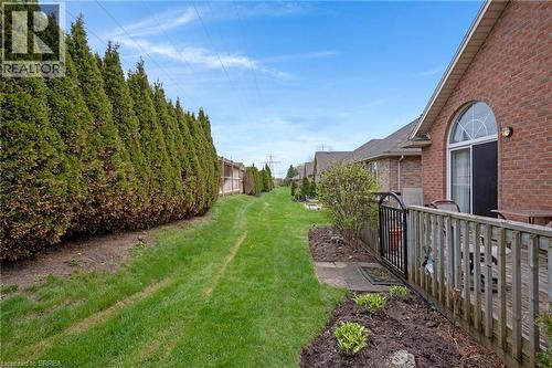 Expansive grassy side yard featuring a tall evergreen hedge and a wood privacy fence - 422 Powerline Road Unit# 10, Brantford, ON - Outdoor