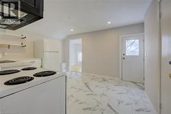 Kitchen area featuring white appliances, a range hood, open shelving, and patterned tile flooring - 