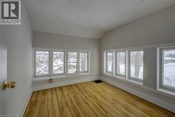 Room featuring light wood-finish flooring, multiple windows providing natural illumination, white trim, recessed ceiling lighting, and a sloped ceiling - 