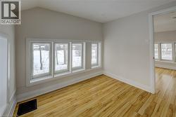 Bright room featuring multiple windows with trim, wood-finish flooring, and crisp white baseboards - 