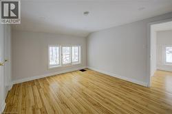 Spacious room featuring light wood-finish flooring, white baseboards, and a triple window unit - 