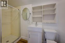 Bathroom featuring a glass-enclosed shower, wood-finish flooring, and a vanity with an integrated sink - 
