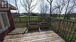 Wood-finish deck with wooden railing overlooking a green space - 