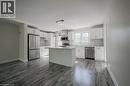 Open-concept kitchen featuring an island, white cabinetry, stainless steel appliances, and wood-finish flooring - 33 Sixth Avenue, Kitchener, ON  - Indoor Photo Showing Kitchen 