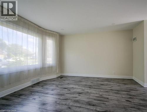 Spacious room featuring wood-finish flooring and a curved bay window - 33 Sixth Avenue, Kitchener, ON - Indoor Photo Showing Other Room