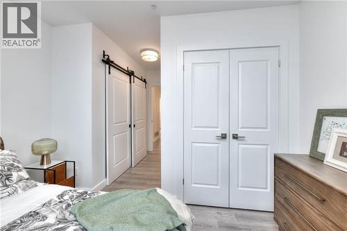 Bedroom with a barn door, a closet, and light wood finished floors - 50 Grand Avenue S Unit# 602, Cambridge, ON - Indoor Photo Showing Bedroom