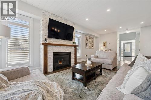 Living room featuring a stacked stone fireplace with a substantial wood mantle, plantation shutters, recessed lighting, and wood-finish flooring - 72 Elmbank Trail, Kitchener, ON - Indoor Photo Showing Living Room With Fireplace