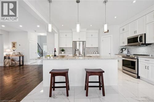 Kitchen featuring a large central island, white cabinetry, stainless steel appliances, pendant lighting, and light-toned tile flooring - 72 Elmbank Trail, Kitchener, ON - Indoor Photo Showing Kitchen With Upgraded Kitchen