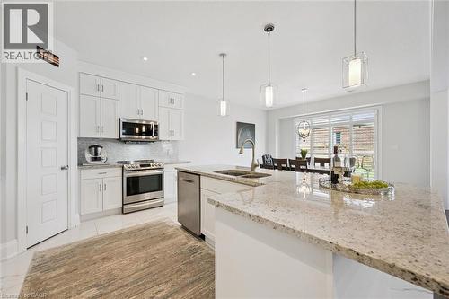 Kitchen featuring a large light-colored countertop island with dual sinks, white cabinetry, stainless steel appliances, and recessed lighting - 72 Elmbank Trail, Kitchener, ON - Indoor Photo Showing Kitchen With Double Sink With Upgraded Kitchen