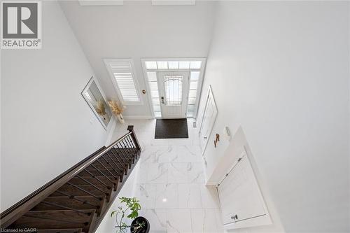 Two-story foyer featuring wood-finish staircase with wrought iron balusters, white marble-look flooring, and a glass-paneled entry door with sidelights - 72 Elmbank Trail, Kitchener, ON - Indoor Photo Showing Other Room