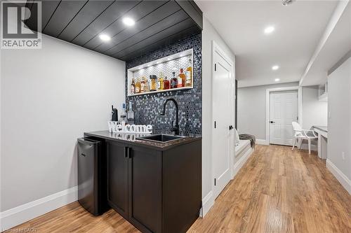 Wet bar featuring dark cabinetry, a black sink, and a contrasting mosaic tile backsplash - 72 Elmbank Trail, Kitchener, ON - Indoor Photo Showing Other Room