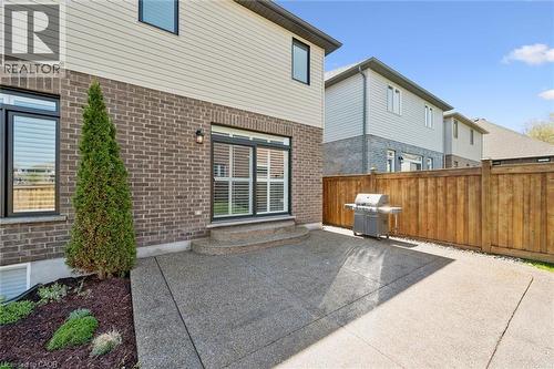 Rear exterior with a concrete patio, brick and siding facade, and a wood fence - 72 Elmbank Trail, Kitchener, ON - Outdoor With Exterior
