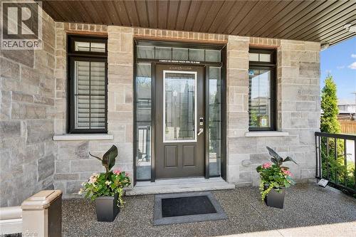 Stone facade entry with a dark-paneled door featuring a decorative glass insert and sidelights - 72 Elmbank Trail, Kitchener, ON - Outdoor