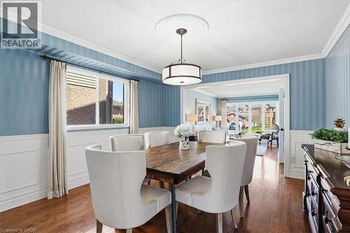 Dining area featuring wood-finish flooring, white wainscoting, an overhead drum pendant light, and an arched doorway opening to additional living space - 19 Forestview Drive, Cambridge, ON - Indoor Photo Showing Dining Room