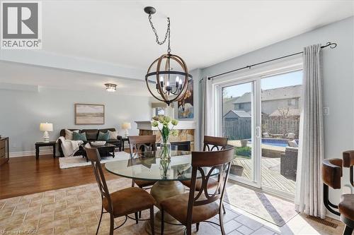 Dining area featuring a contemporary spherical chandelier and a glass-top table - 19 Forestview Drive, Cambridge, ON - Indoor Photo Showing Dining Room