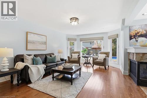 Bright living space featuring warm wood-finish flooring, a stone-clad fireplace with a white mantel, and recessed lighting - 19 Forestview Drive, Cambridge, ON - Indoor Photo Showing Living Room With Fireplace