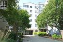 Modern building exterior featuring a stone accent wall, large windows, and a paved entrance - 175 Hunter Street E Unit# 301, Hamilton, ON  - Outdoor 